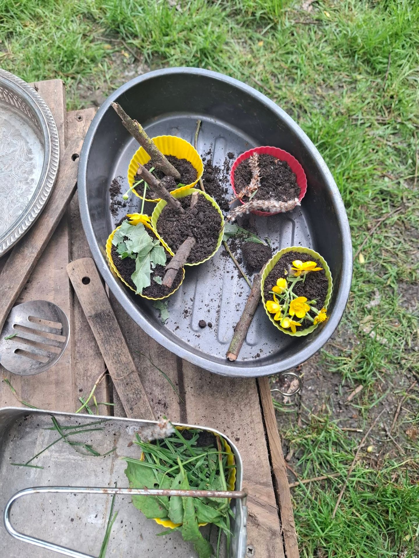 Mud kitchen tray with buttercups, leaves and sticks