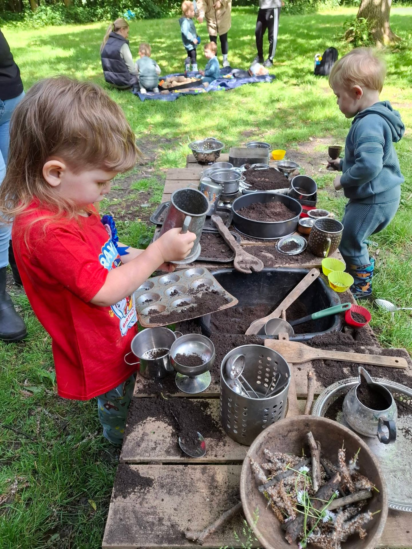Woodland mud kitchen with wooden crates and tin pots